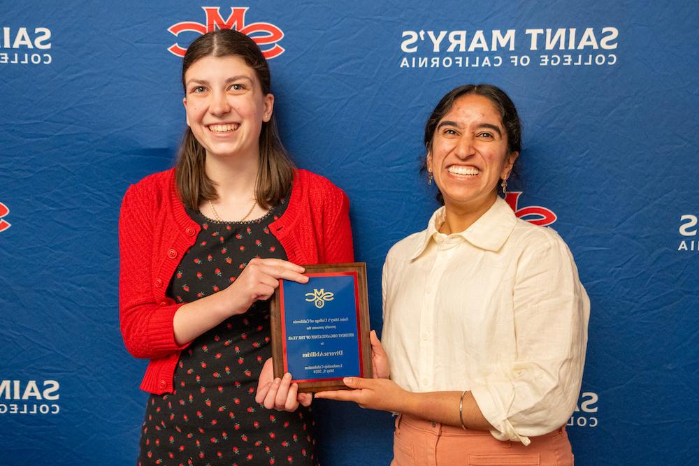 多元化学生领袖Sahiba Kuar Dogra和Molly Floberg举着2024年学生领袖奖的牌匾