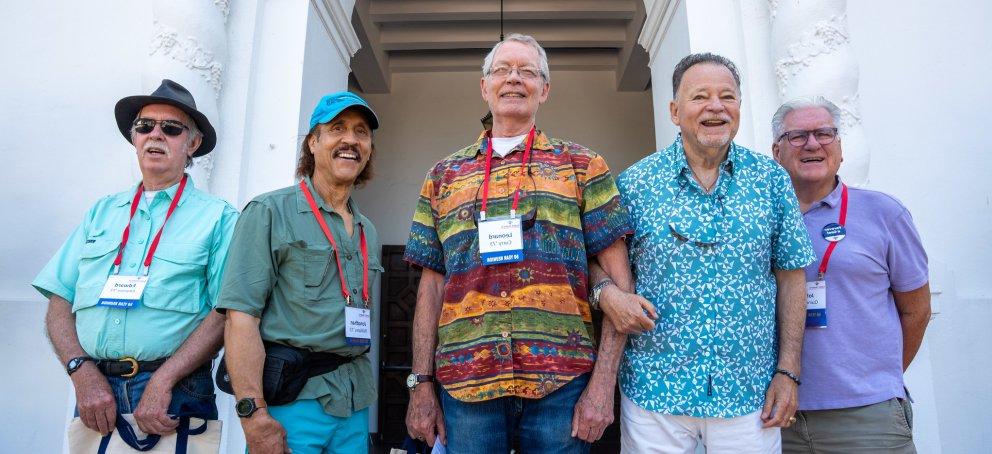 Five alumni stand arm-in-arm in front of The Chapel